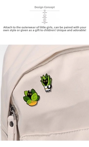 Detail of two black cat enamel pins pinned on a canvas backpack featuring green plants