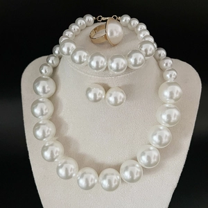 Close-up of elegant white pearl jewelry set with gold finish on a beige mannequin