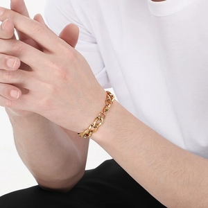 Détail d'un bracelet gourmette épais en finition or 18 carats porté par un modèle