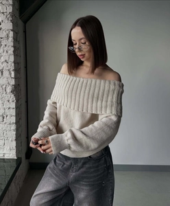 Detail of off-white off-the-shoulder knitted sweater with vertical ribbed texture and long sleeves