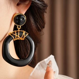 Gros plan de boucles d'oreilles vintage en résine noir et or sur le mannequin