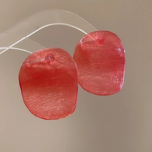 Macro shot of red resin earrings with a brushed texture and irregular oval shape