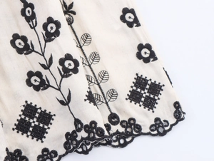 Macro detail of bohemian floral embroidery and wavy lace hem on cotton linen dress