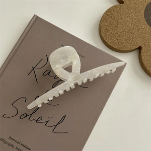 Dettaglio molletta per capelli in acetato bianco perlato con incisione France Handmade su libro
