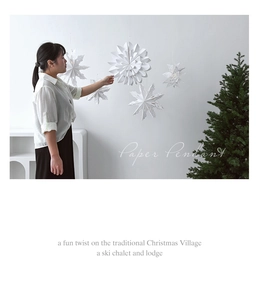White paper snowflake pendant hanging on a wall with festive Christmas tree decor