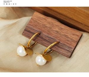 Detail of vintage gold hoop earrings with white pearl pendants on wood and silk