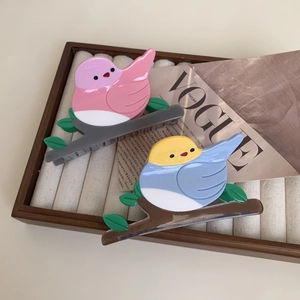 Bird shaped acetate hair clips in pink and blue on velvet tray shown at a 45-degree angle