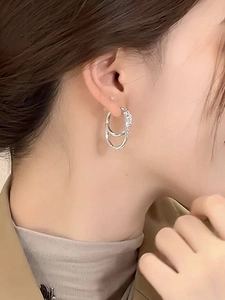 Close-up detail of 18k silver double round hoop earrings worn on a model's ear