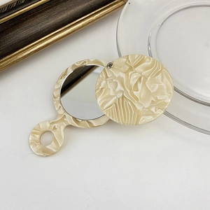 Close-up of portable cream marble acetate handheld mirror with sliding protective cover