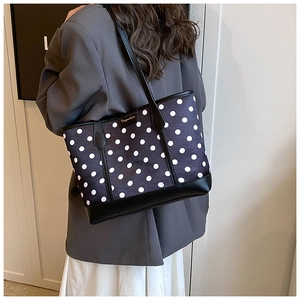 Detail of black canvas tote with white polka dots and premium leather handles