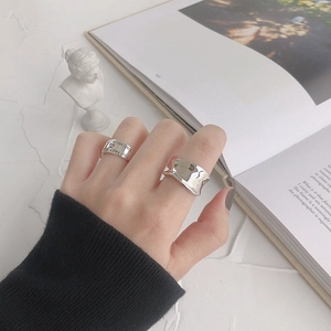 Minimalist S925 sterling silver irregular wave and engraved band rings on a book
