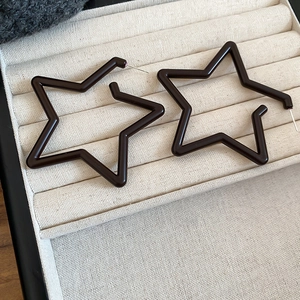 Detailed view of black star-shaped acrylic hoop earrings in a beige velvet jewelry box