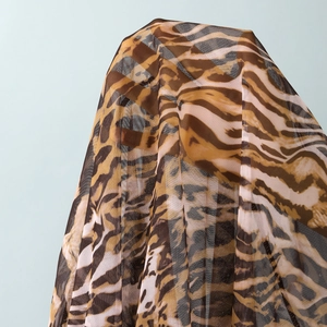 Detail of breathable leopard print mesh fabric showing lightweight texture for beach cover-up