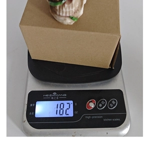 Detailed view of skull resin ornament being weighed on a scale for product mass