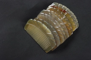 Macro shot of natural textured translucent yak horn combs with carved wavy edges