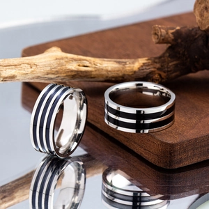 Polished titanium steel striped enamel rings set displayed on a wooden base