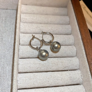 Détail de créoles argentées avec perles grises sur un plateau à bijoux en velours beige