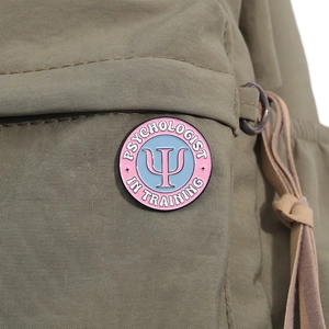 Detail of Psychologist in Training enamel pin with pink Psi symbol on green canvas bag