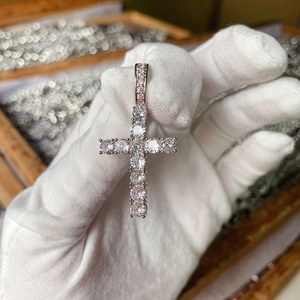 Close-up of silver-tone cross pendant with shimmering pavé zircon stones on white glove