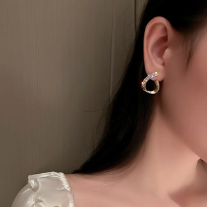 Elegant gold drop earrings with diamond-encrusted twisted C-shape design on female model