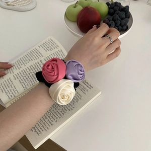 Detailed close-up of pink, purple and white satin rose flower hair scrunchies on a book