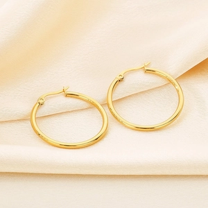Macro detail of polished gold hoop earrings resting on soft fabric with natural light