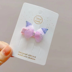 Detail of a purple butterfly hair clip with rhinestones on a pink duckbill clip
