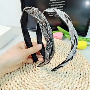 Detail showing two braided rhinestone headbands in black and silver finishes on a mat