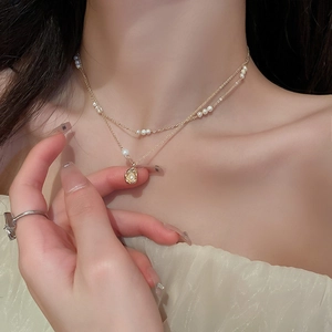 Détail d'un collier double rang doré avec perles porté sur le cou d'un mannequin