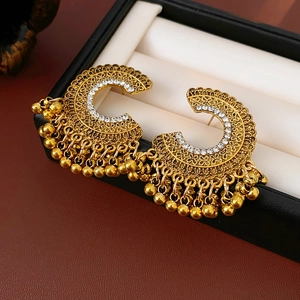 Vista macro dettagliata di orecchini Jhumka vintage dorati con strass e nappe di perline