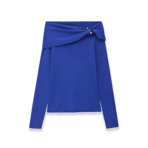 Detail of royal blue off-shoulder knit top with an elegant gold decorative pin