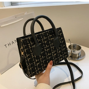 Macro shot of black tweed handbag with gold thread texture and elegant top handle