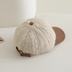 Détail de casquette beige en peluche avec visière en velours marron et texture douce
