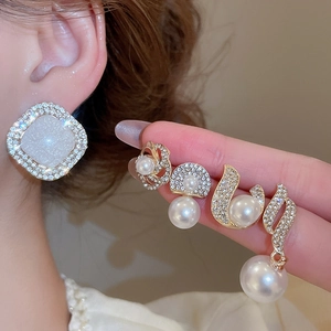 Close-up of elegant gold and pearl earrings set with sparkling diamond accents on ears
