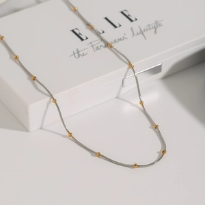Two-tone stainless steel snake chain necklace with gold bead accents on white display