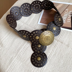 Detail of round dark brown leather discs with metal rivets and vintage relief buckle