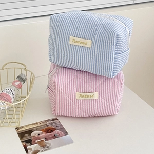 Pastel striped quilted cotton makeup bags in sky blue and pink stacked on white desk