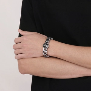 Detail of men's chunky Cuban link bracelet with vintage skull emblem on model's wrist