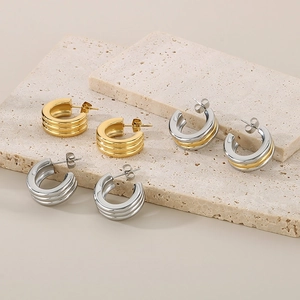 Detail of ribbed C-shape hoop earrings in gold, silver, and two-tone finishes on stone