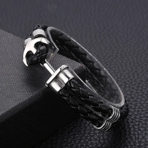 Macro shot of double-layer black leather woven bracelet with silver metal anchor buckle