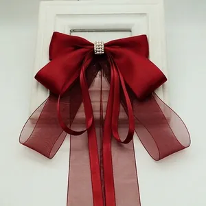 Detail of red layered satin bow hair clip with faux pearl and rhinestone embellishments