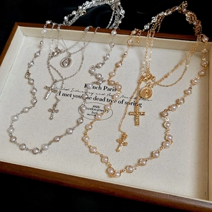 Detail of layered gold and silver cross necklaces with pearls on a velvet display tray