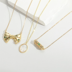 Three 18K gold plated necklaces featuring bow, oval shell and hollow bead pendants