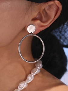 Gros plan de boucles d'oreilles anneaux en métal argenté poli portées par un mannequin