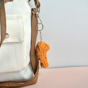 Realistic fried chicken leg PVC keychain accessory attached to a canvas bag strap