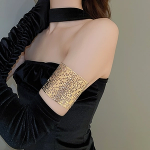 Detail view of gold hollow geometric woven arm cuff on black velvet glove background