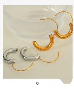 Close-up of chunky C-shape hoop earrings in polished gold and silver metallic finishes
