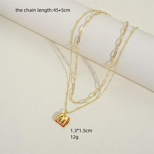 French vintage double layer gold initial M pendant necklace shown on a white pedestal
