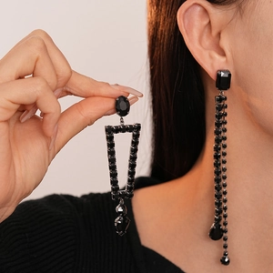 Dark style asymmetric geometric tassel earrings with black crystals on a model