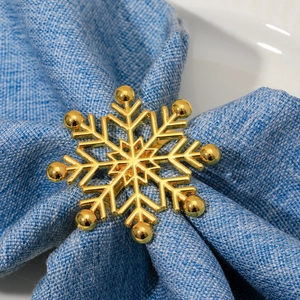 Golden snowflake napkin ring with rhinestones on a blue napkin for festive dining décor